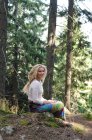 Жінка сидить у лісі і дивиться на камеру — стокове фото