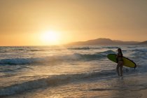 Silhouette d'une femme portant une planche de surf, plage de Los Lances, Tarifa, Cadix, Andalousie, Espagne — Photo de stock