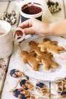 Boy hand reaching for a cup of tea and gingerbread man cookies — Stock Photo