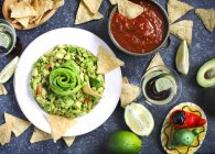 Top view of tasty guacamole, tortilla chips, salsa and lime — Stock Photo
