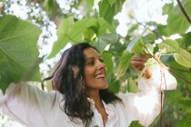 Retrato de uma mulher sorridente entre árvores na floresta — Fotografia de Stock