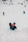 Мальчик катается на санках с горы зимой — стоковое фото