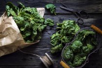 Fresh spinach wrapped in paper over black table — Stock Photo