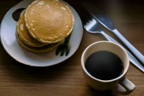 Stack of pancakes with black coffee over table — Stock Photo