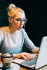 Woman using laptop at office on black background — Stock Photo