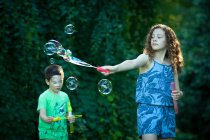 Мальчик и девочка пускают огромные мыльные пузыри — стоковое фото