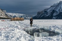 Femme debout près d'un trou de plongée sur glace, Banff, Alberta, Canada — Photo de stock