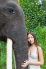 Woman leaning against elephant with her eyes closed, Tegallalang, Bali, Indonesia — Stock Photo