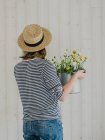 Mulher segurando um balde com flores frescas — Fotografia de Stock