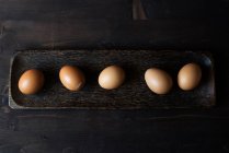 Cinco ovos em um prato de madeira — Fotografia de Stock