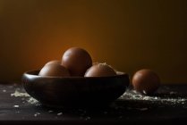 Huevos en un tazón de madera con serrín, a nivel de superficie - foto de stock