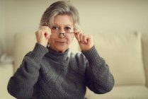 Senior mulher colocando em seus óculos — Fotografia de Stock