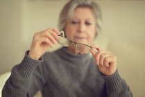 Старшая женщина надевает очки — стоковое фото