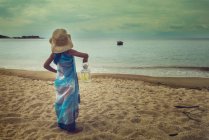 Mädchen steht mit Laterne am Strand — Stockfoto