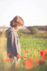 Junge steht in einem Mohnfeld — Stockfoto