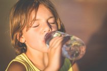 Niño bebiendo botella de agua en la naturaleza - foto de stock