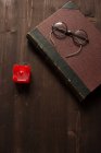 Vieux livre, bougie rouge et lunettes sur une table en bois — Photo de stock