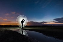 Silhueta de homem em pé no campo cercado por halo de luz — Fotografia de Stock
