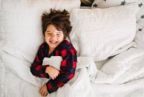 Portrait of a boy lying in bed laughing — Stock Photo
