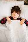 Retrato de un niño sonriente acostado en la cama - foto de stock