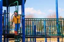 Ragazzo che gioca nel parco giochi nella soleggiata giornata autunnale — Foto stock