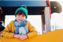 Ragazzo in abiti caldi in piedi sul telaio di arrampicata nel parco giochi — Foto stock