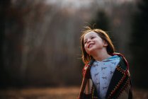 Retrato de uma menina embrulhada em uma colcha de retalhos olhando para cima — Fotografia de Stock