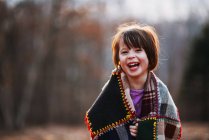 Porträt eines Mädchens, das in eine Decke gehüllt ist und lacht — Stockfoto