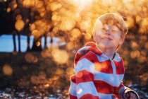 Retrato de um menino sorridente na floresta ao pôr-do-sol — Fotografia de Stock