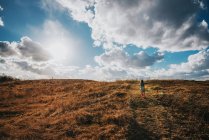 Chica corriendo por una colina con una cometa en la naturaleza - foto de stock