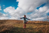Дівчина стоїть з простягнутими руками на вітрі — стокове фото
