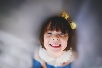 Porträt eines lächelnden Mädchens mit Schleife, das durch einen Vorhang nach oben blickt — Stockfoto