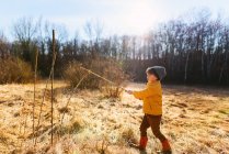 Мальчик играет с палкой в лесу — стоковое фото