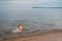 Entzückender kleiner Junge schwimmt im See — Stockfoto