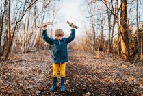 Очаровательный маленький мальчик играет в одиночестве в осеннем лесу — стоковое фото