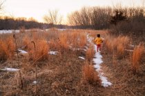 Boy running through rural landscape in winter — Stock Photo