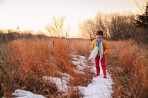 Хлопчик стоїть в сільському зимовому пейзажі — стокове фото