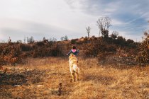 Hund jagt ein Mädchen, das einen Hügel hinaufläuft — Stockfoto
