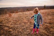 Niño de pie en el paisaje rural sosteniendo un palo - foto de stock