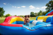 Two boys hugging on an inflatable water slide — Stock Photo