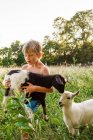 Мальчик с очаровательной козой на поле — стоковое фото
