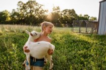 Boy carrying adorable goat on nature — Stock Photo
