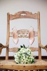 Весільний букет і взуття нареченої на стільці — стокове фото