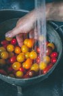 Man hand washing cherry tomatoes in colander, closeup view — Stock Photo