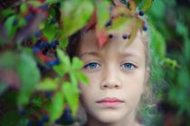 Retrato de uma menina olhando através de folhas — Fotografia de Stock