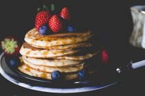 Stapel Pfannkuchen mit Ahornsirup, frischen Erdbeeren und Blaubeeren — Stockfoto