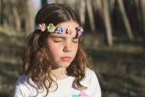 Portrait of a girl with her eyes closed wearing a flower wreath on her head — Stock Photo