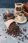 Кавомолка з мішками кавових зерен і чашкою кави — стокове фото
