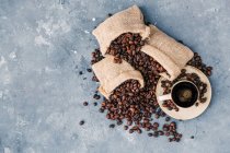 Мішки з кавовими зернами і чашкою кави — стокове фото