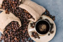Xícara de café e grãos de café sobre a mesa — Fotografia de Stock